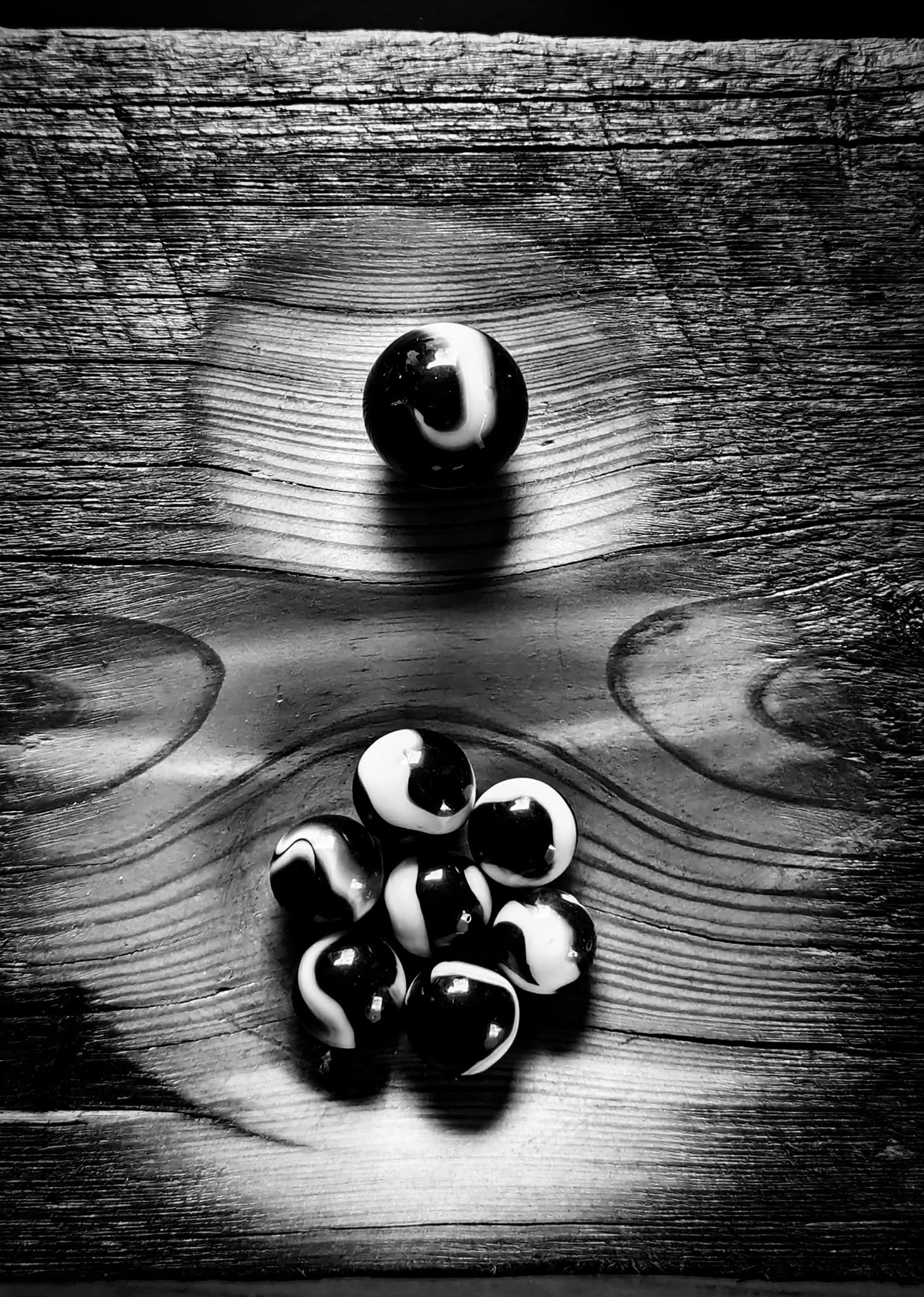 Black and white photograph of glass marbles resting in a carved wooden surface
